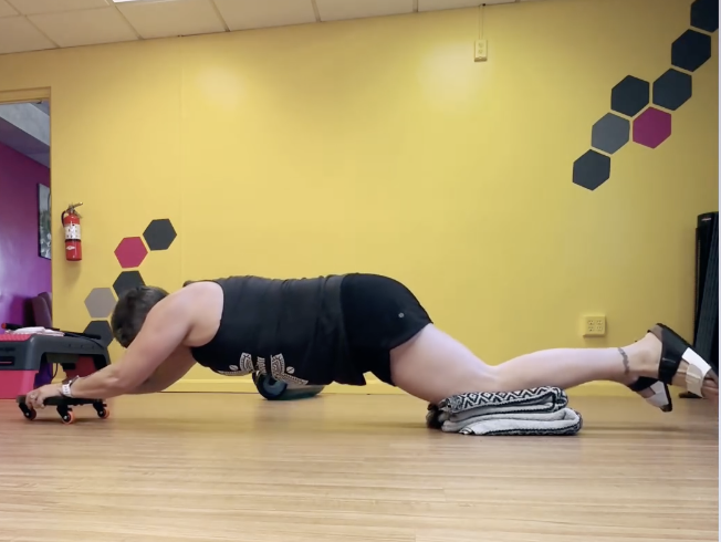 gretchen schock is on her knees and using a core coaster over her head to engage in an abdominal exercise